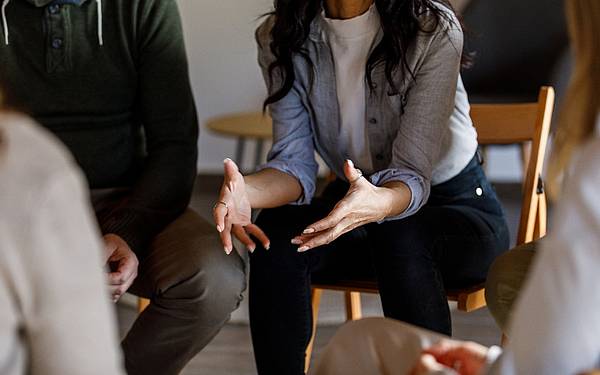 Sitzende Gruppe im Gespräch, eine Person teilt Ihre Themen mit anderen © iStock / fotostorm