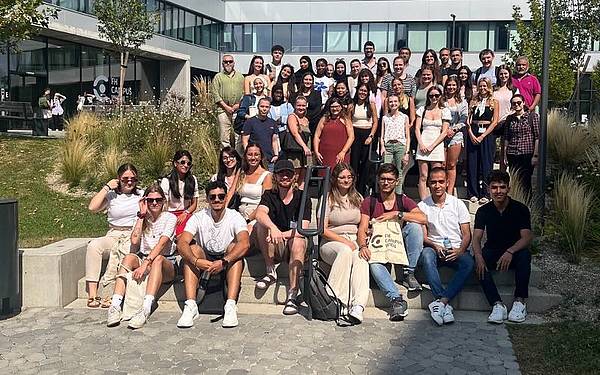 Eine Gruppe Studierender sitzt auf einer Treppe und posiert für ein Foto