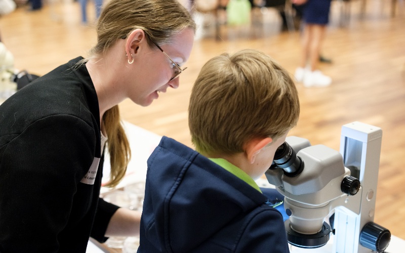 Eine Frau und ein Kind sitzen vor einem Mikroskop